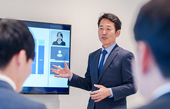 モニターの前で講義している